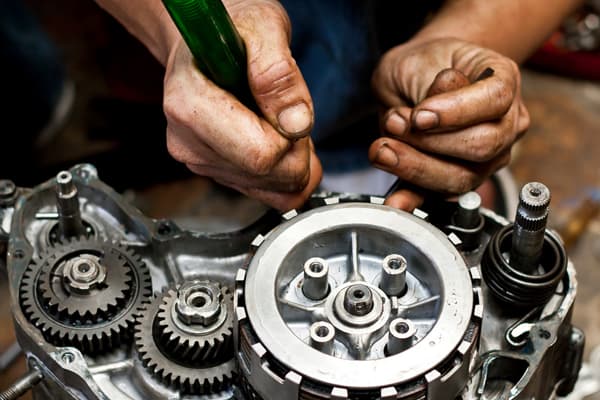 Hands repairing a car gearbox and clutch assembly
